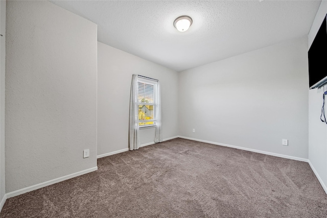 carpeted empty room featuring a textured ceiling and baseboards