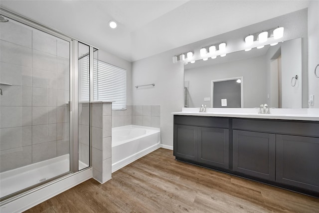 full bath with a sink, wood finished floors, a bath, double vanity, and a stall shower