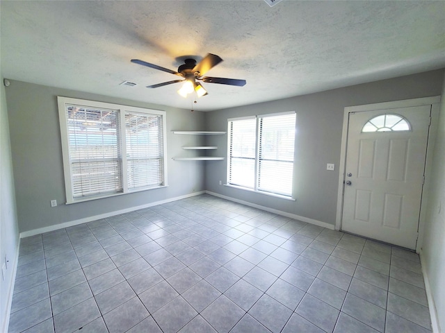 foyer featuring visible vents, ceiling fan, a textured ceiling, baseboards, and tile patterned floors