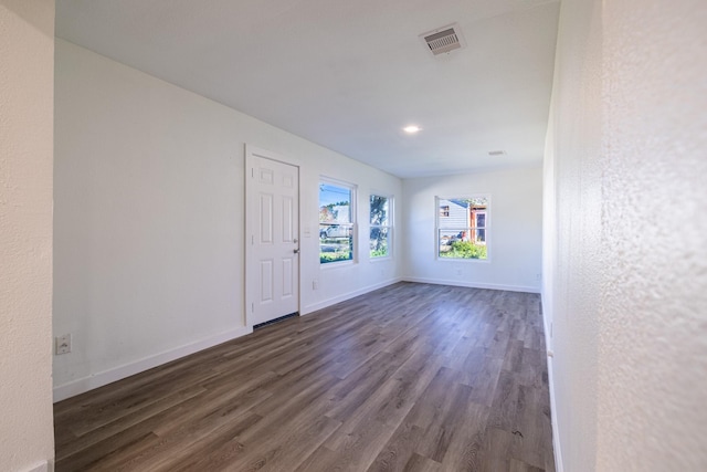 unfurnished room with dark wood-style floors, visible vents, and baseboards