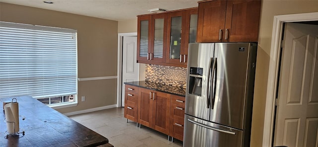 811 Piney Ridge Dr, Friendswood, TX 77546 - kitchen with stainless steel refrigerator with ice dispenser, tasteful backsplash, glass insert cabinets, brown cabinetry, and dark stone countertops