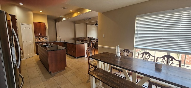 811 Piney Ridge Dr, Friendswood, TX 77546 - kitchen with freestanding refrigerator, a kitchen island, dark countertops, backsplash, and light tile patterned floors