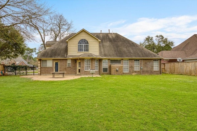 rear view of house with a patio, brick siding, a lawn, and fence