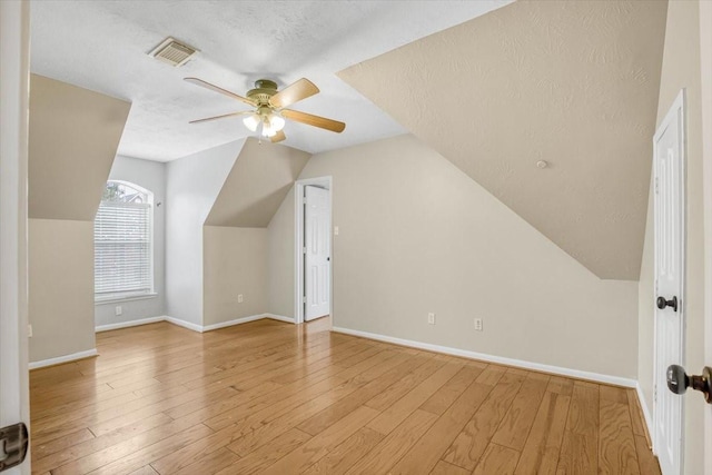 bonus room featuring ceiling fan, a textured ceiling, wood finished floors, visible vents, and baseboards