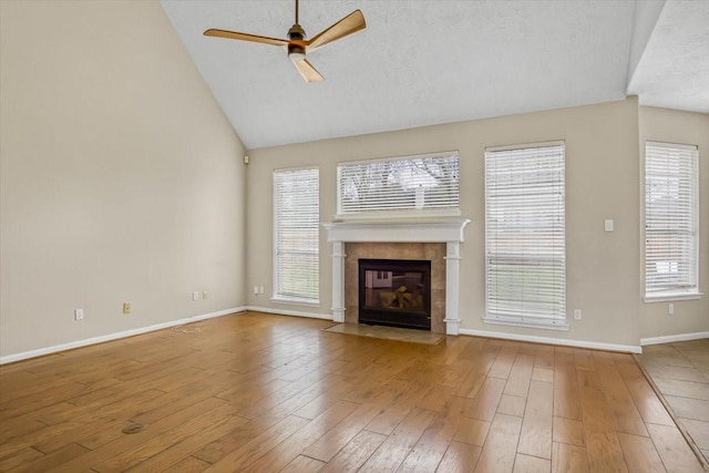 unfurnished living room with lofted ceiling, ceiling fan, a fireplace, wood finished floors, and baseboards