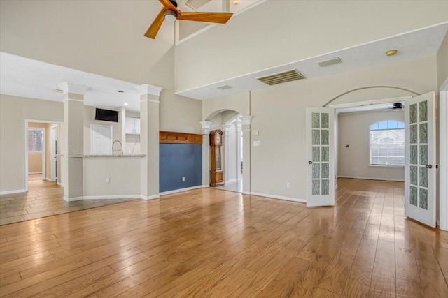 unfurnished living room featuring arched walkways, ceiling fan, and hardwood / wood-style flooring