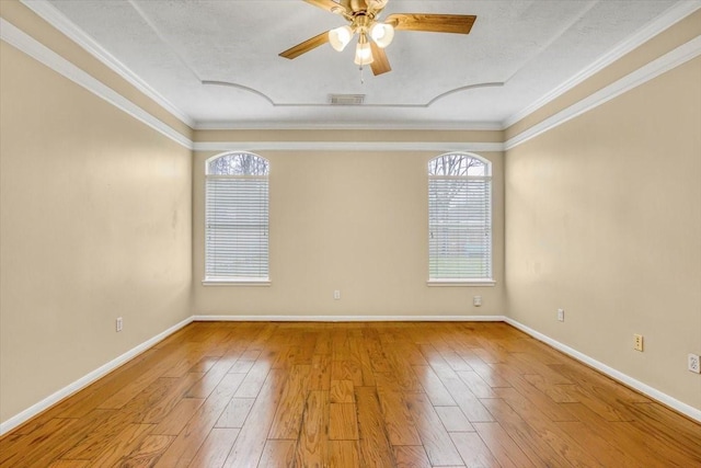 empty room with ceiling fan, ornamental molding, wood finished floors, and baseboards