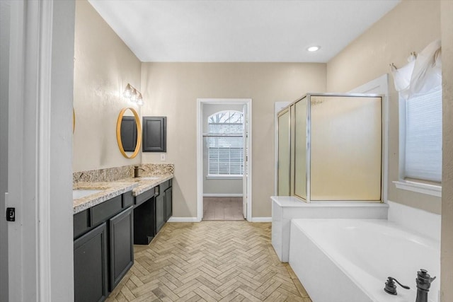 bathroom featuring a garden tub, double vanity, a sink, a shower stall, and baseboards