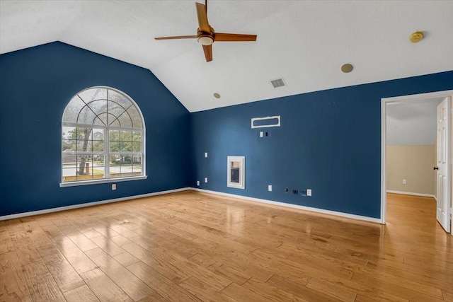 empty room with lofted ceiling, ceiling fan, wood finished floors, visible vents, and baseboards