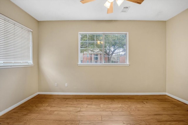 unfurnished room with ceiling fan, light wood-type flooring, visible vents, and baseboards