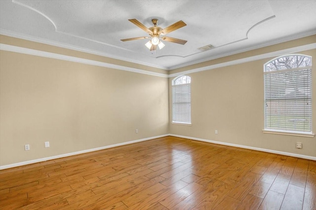 spare room featuring hardwood / wood-style flooring, baseboards, visible vents, and a ceiling fan