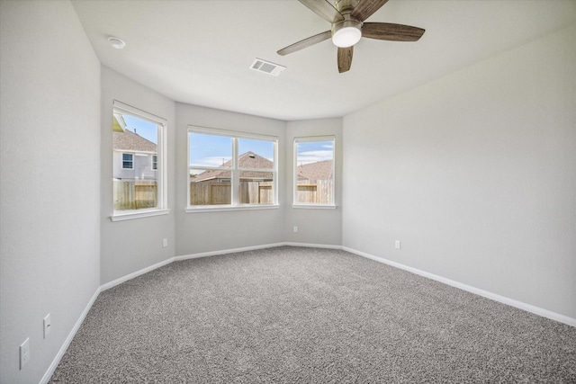 carpeted spare room featuring visible vents, ceiling fan, and baseboards