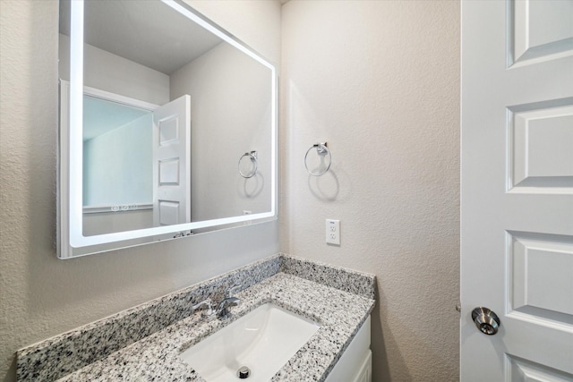 bathroom featuring vanity and a textured wall