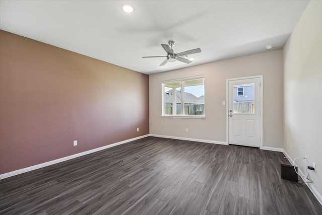 spare room featuring visible vents, a ceiling fan, baseboards, and dark wood-style flooring