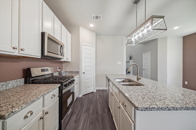 kitchen with visible vents, a kitchen island with sink, a sink, dark wood-type flooring, and appliances with stainless steel finishes