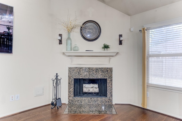 unfurnished living room featuring wood finished floors, a high end fireplace, and baseboards