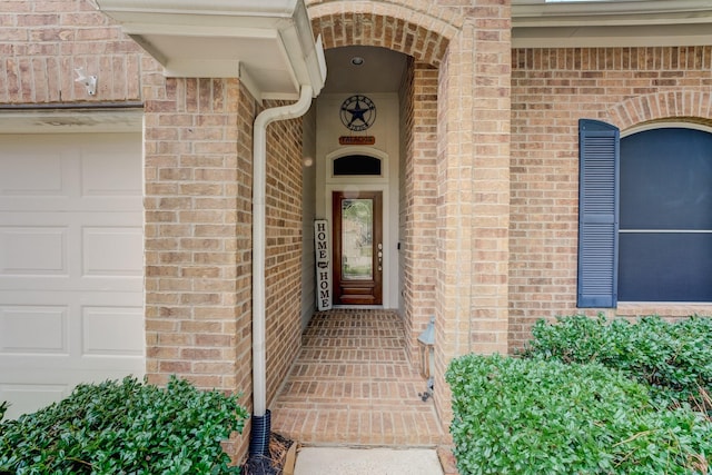 entrance to property featuring brick siding and an attached garage