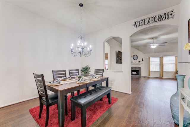 dining room featuring ceiling fan with notable chandelier, hardwood / wood-style floors, a high end fireplace, and baseboards