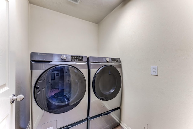 washroom with laundry area, separate washer and dryer, and baseboards