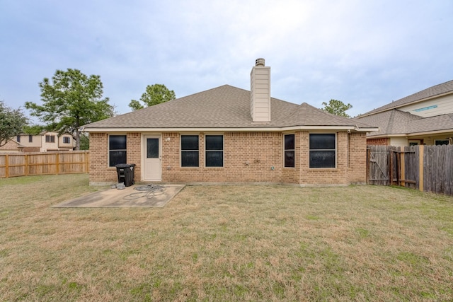 back of house with brick siding, a yard, a chimney, a patio area, and a fenced backyard