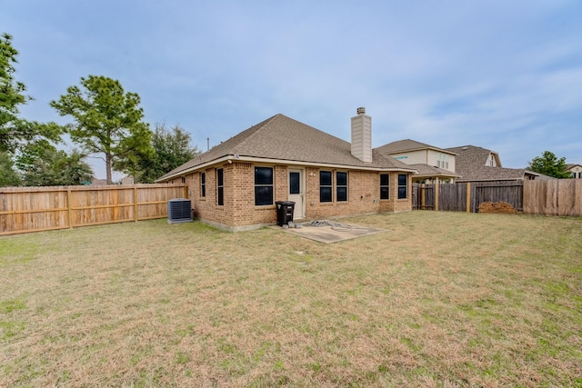 back of property featuring brick siding, a lawn, a fenced backyard, and central AC unit