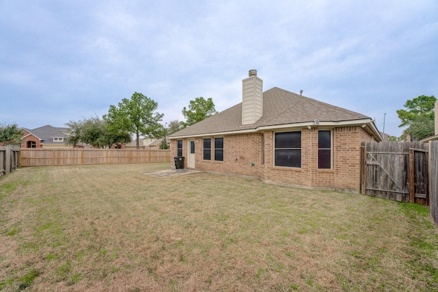 back of property with a yard, a fenced backyard, a chimney, and brick siding