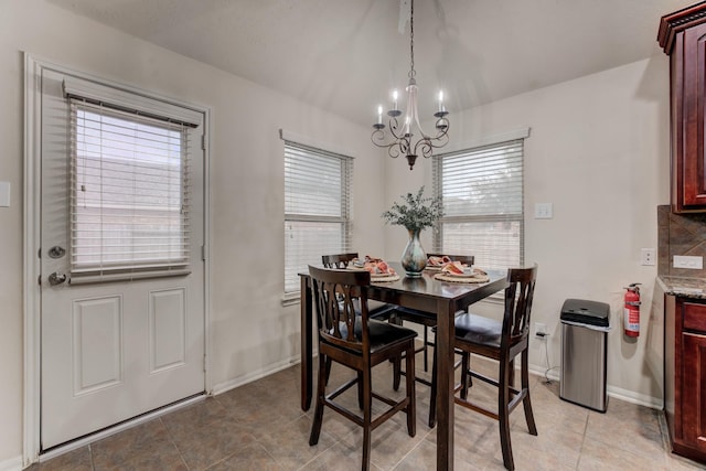 dining area with light tile patterned floors, baseboards, and an inviting chandelier