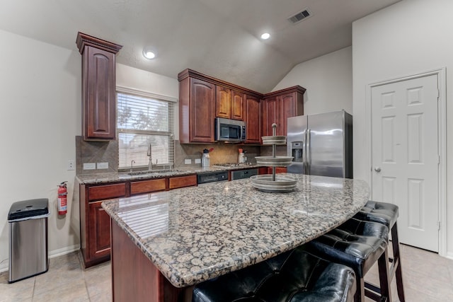 kitchen with a breakfast bar, a sink, visible vents, appliances with stainless steel finishes, and decorative backsplash