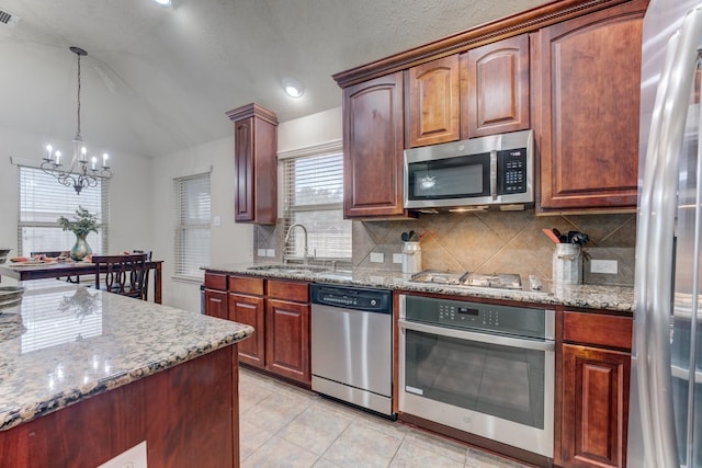 kitchen with visible vents, light stone countertops, stainless steel appliances, a chandelier, and a sink