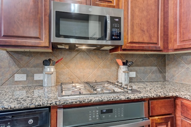 kitchen featuring light stone counters, stainless steel appliances, and backsplash