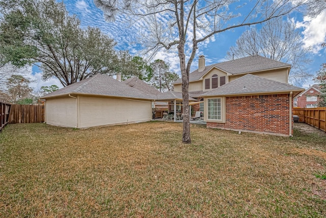 back of property featuring a garage, a yard, a fenced backyard, and brick siding