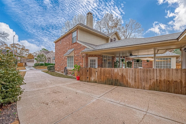 view of side of property with brick siding, a chimney, a fenced front yard, and a shingled roof