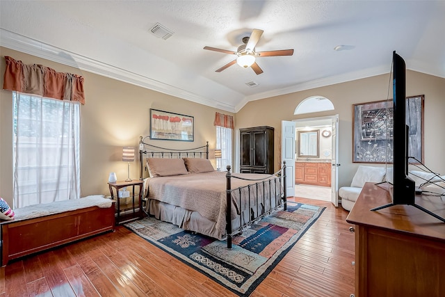 bedroom with visible vents, ornamental molding, lofted ceiling, and hardwood / wood-style flooring