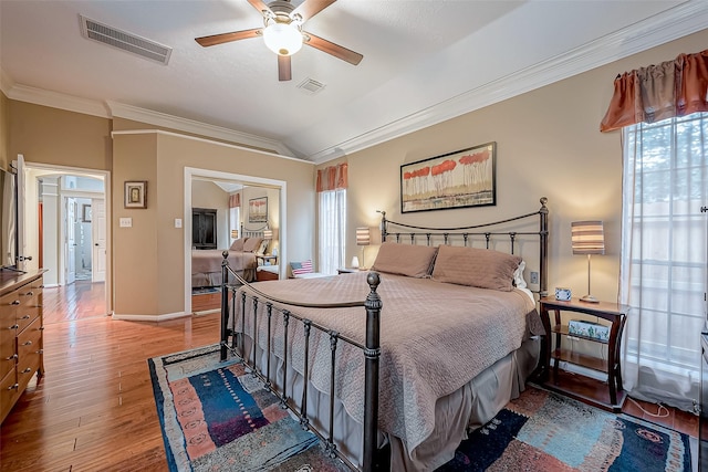 bedroom with vaulted ceiling, visible vents, ornamental molding, and wood finished floors