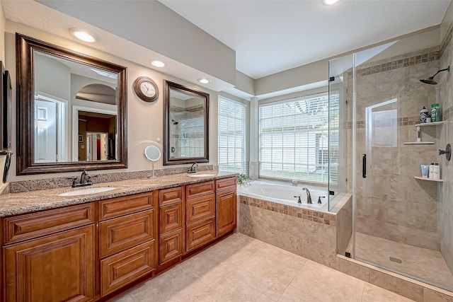 bathroom with a bath, a shower stall, double vanity, and a sink