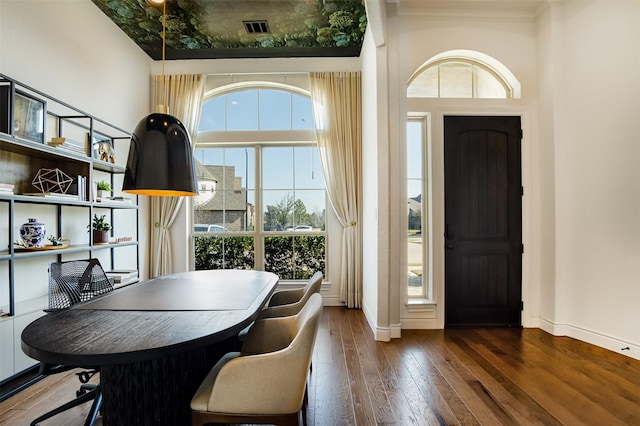 dining room with visible vents, crown molding, baseboards, a towering ceiling, and wood-type flooring