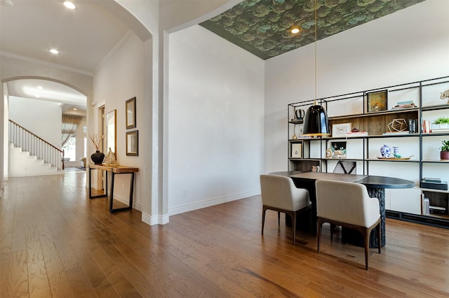 home office featuring baseboards, arched walkways, hardwood / wood-style floors, and crown molding