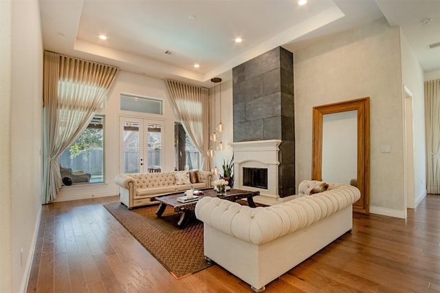 living room with a tray ceiling, french doors, a fireplace, and wood-type flooring