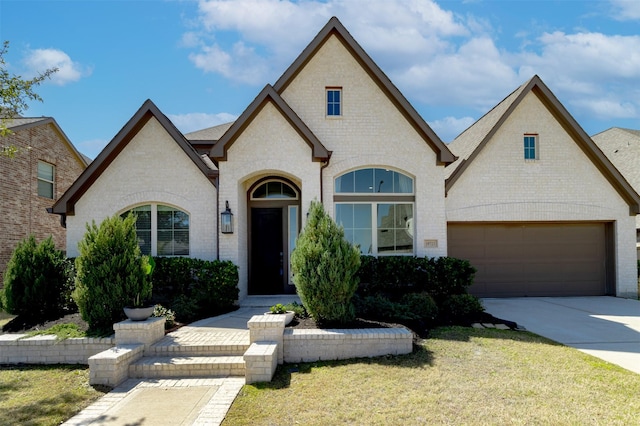 french country inspired facade with a front yard, brick siding, and driveway