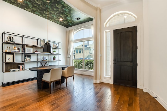 office area featuring hardwood / wood-style floors, baseboards, visible vents, and ornamental molding