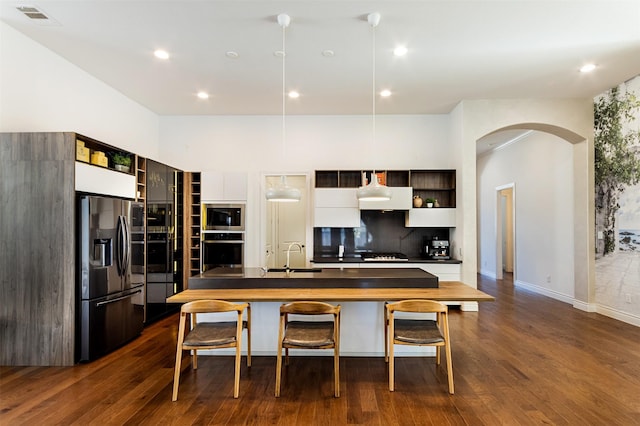 kitchen with arched walkways, appliances with stainless steel finishes, modern cabinets, and open shelves