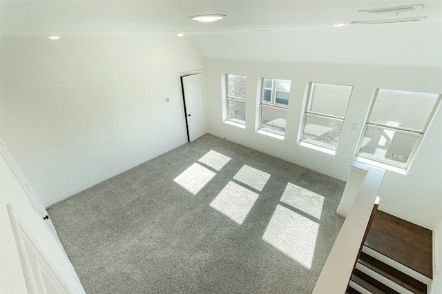 unfurnished room featuring baseboards, carpet floors, visible vents, and vaulted ceiling