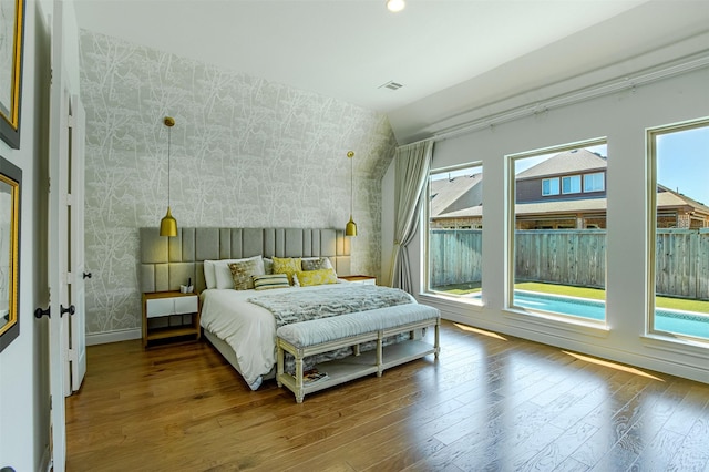 bedroom with baseboards, hardwood / wood-style floors, vaulted ceiling, and wallpapered walls