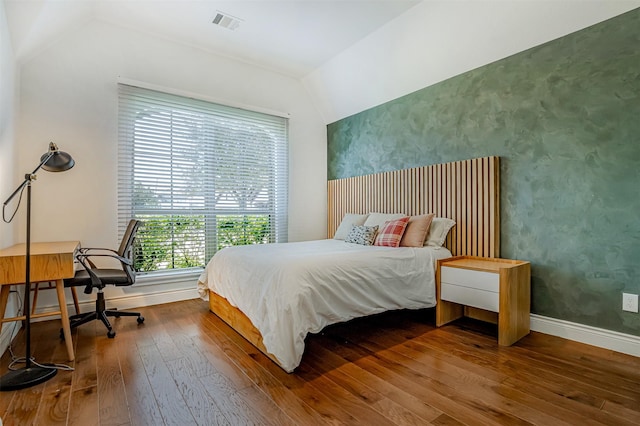 bedroom featuring visible vents, baseboards, vaulted ceiling, and hardwood / wood-style flooring