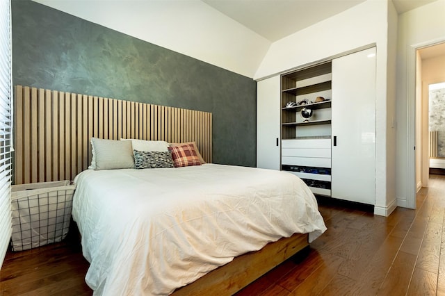 bedroom with baseboards, wood-type flooring, a closet, and vaulted ceiling