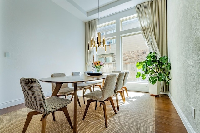 dining area featuring baseboards, an inviting chandelier, wood finished floors, and a textured wall