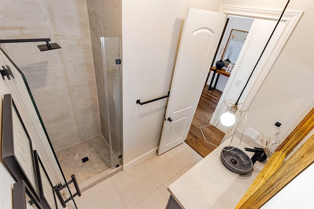 bathroom with tile patterned floors, a shower stall, and a sink