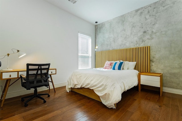 bedroom with an accent wall, baseboards, and hardwood / wood-style floors