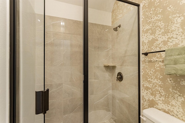 bathroom featuring a stall shower, toilet, and wallpapered walls