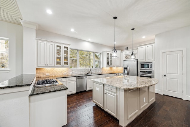 kitchen with stainless steel appliances, dark wood-style flooring, a sink, and backsplash